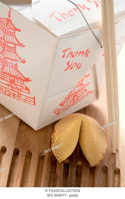 Asian snack in take-away box with chopsticks, fortune cookie