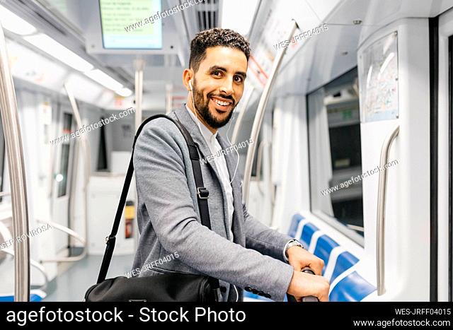 Portrait of smiling young businessman with earphones on the subway