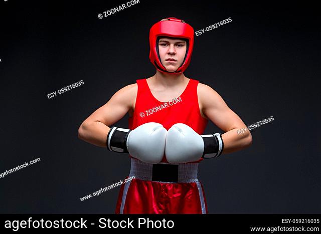 Teenage boxer in red form and white boxing gloves. Studio shot on black background