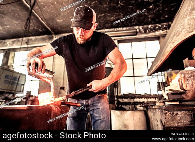 Knife maker working scattering borax over hot damask steel