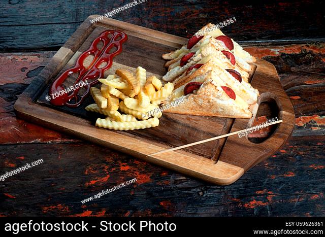 Sandwiches with Turkish sausage (sucuk) and cheese served aise with french fries isolated on rustic wooden table