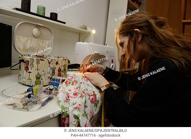 A young woman sews in her apartment in Berlin, Germany, 13 November 2013. More and more women start to sew at the moment