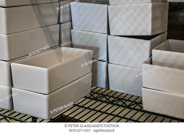 Stacks of white rectangle ceramic food containers on a metal wire rack