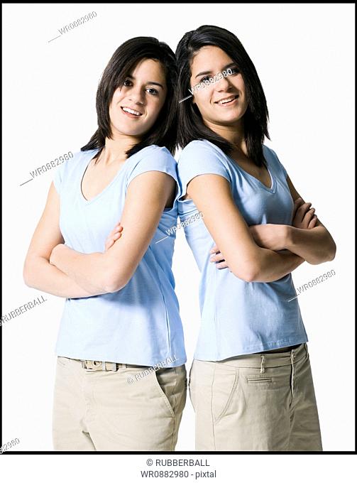 Portrait of two teenage girls standing back to back