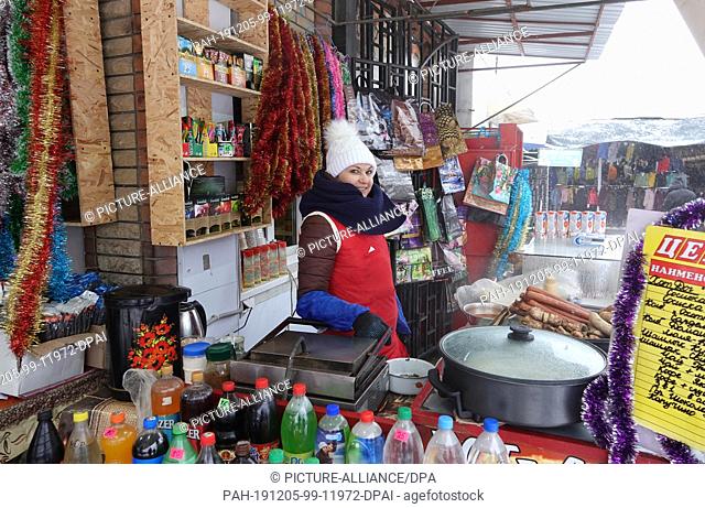 03 December 2019, Ukraine, Luhansk: The saleswoman Olga offers hot dogs, shashlik and hot drinks at her stand on the city's central market