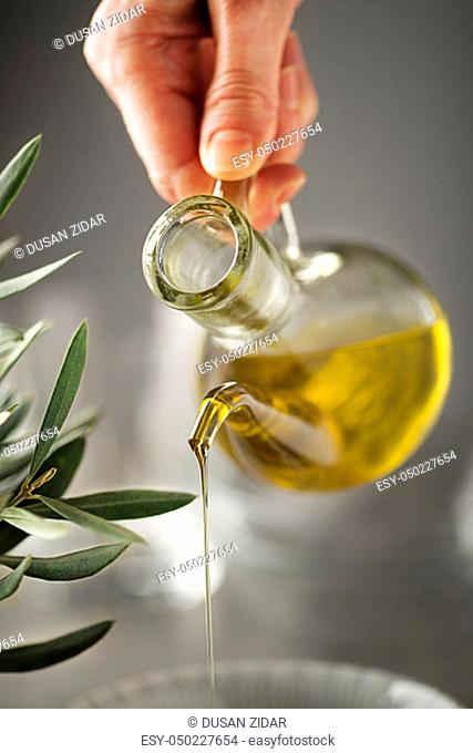 Preparing healthy meal with olive oil. Bottle of Extra virgin oil pouring in to bowl. Healthy food concept