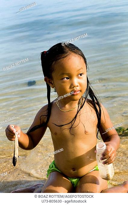 A cute girl plays with a small fish, Phuket, Thailand