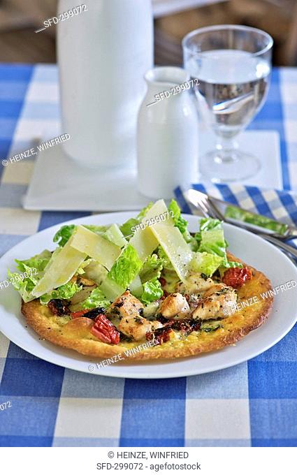 Pizza topped with chicken, romaine lettuce and cheese