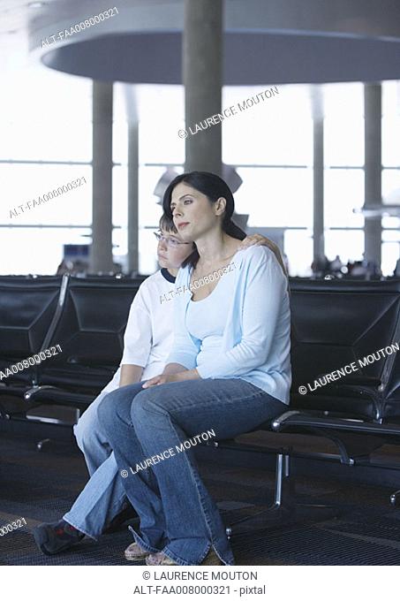 Mother and son sitting in airport lounge