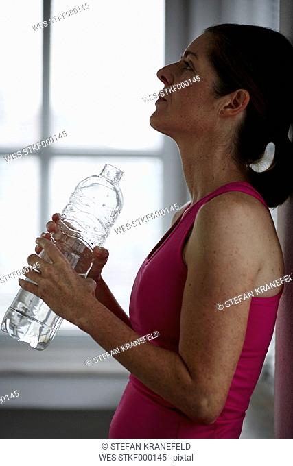 Germany, Duesseldorf, Mature woman drinking water after exercise