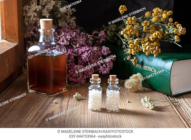 Two bottles of homeopathic globules with dried herbs and a materia medica, i. e. a list of remedies and their therapeutic properties