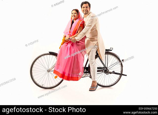 A RURAL COUPLE SITTING TOGETHER ON NEW BICYCLE AND POSING