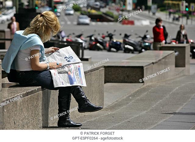WOMAN SITTING ON THE SIDEWALK READING A PAPER, PLAZA DE COLON, MADRID, SPAIN