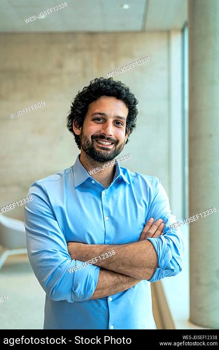 Smiling businessman with arms crossed standing in office
