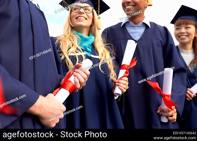 graduate students in mortar boards with diplomas