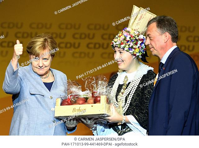 Altenland Flowerqueen Hilke Loesing (M)Â presents Chancellor Angela Merkel (L) a selection of her favourite apple Boskop, Helmut Dammann-Tamke