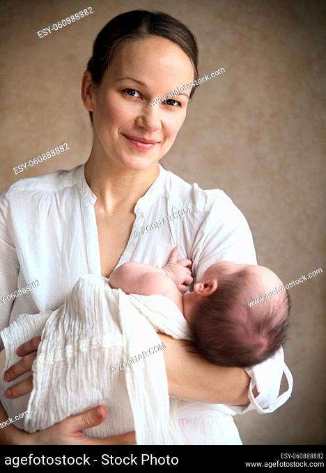 One month old baby boy falling asleep in the arms of her mother