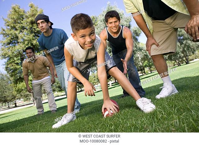 Boy 13-15 playing football with group of men