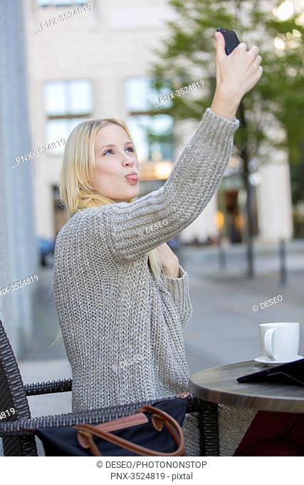 Playful pretty young woman doing a selfie in a Cafe in city center