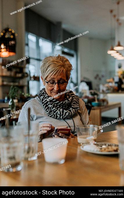 Senior woman using phone in cafe