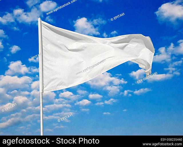White flag against a blue sky with clouds fluttering in the wind