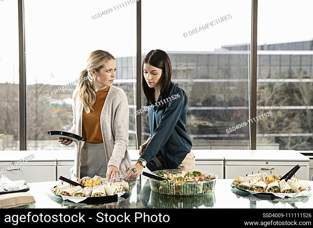 Two people reaching for the same item on a lunch buffet