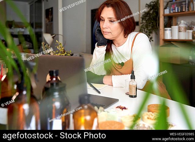 Female entrepreneur working on laptop at workshop