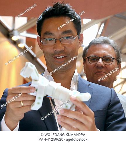 German economy minister Philipp Roesler (FDP, C) observes a robot dog of company kinematics in Berlin, Germany, 24 July 2013