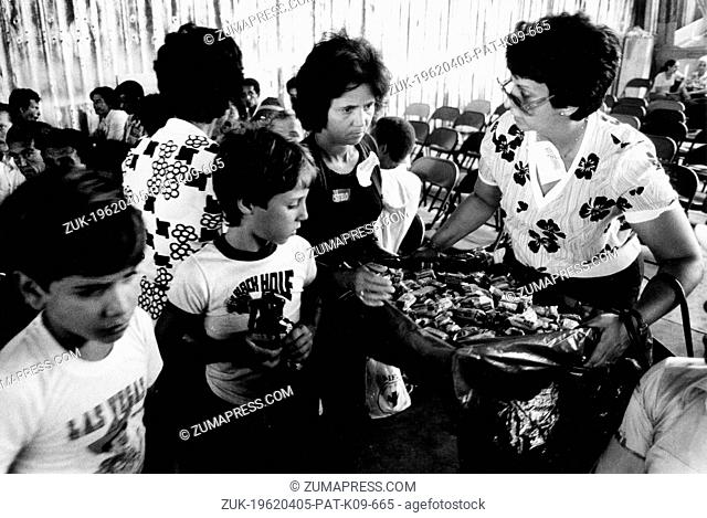 Date Unknown - Miami, FL, U.S. - Cuban refugees crowd around a volunteer as she distributes candy to the people waiting to be processed at the Opa Locka center