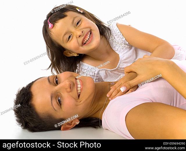 Smiling mother and daughter lying on the floor. Looking at camera, white background
