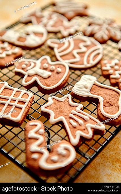 Fresh baked and prepared Christmas shaped gingerbread cookies placed on steel grill frame on a table. View from above