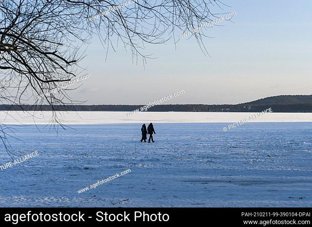 10 February 2021, Berlin: Two people are walking on the frozen Müggelsee Berlin. Photo: Kira Hofmann/dpa-Zentralbild/ZB. - Berlin/Berlin/Germany