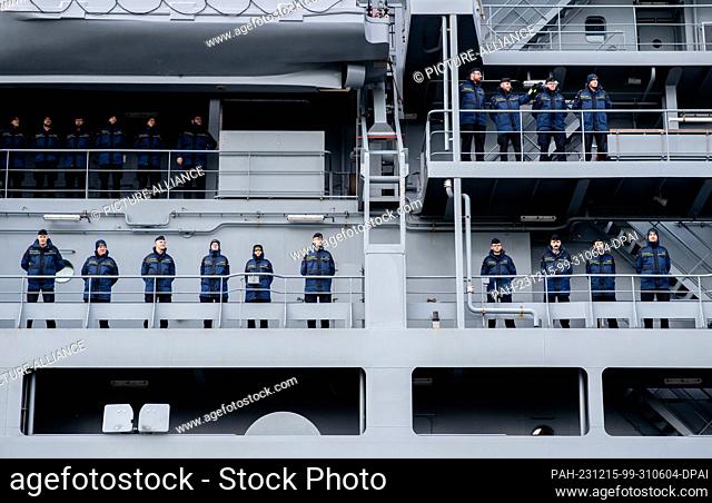 15 December 2023, Lower Saxony, Wilhelmshaven: Crew members stand on board the task force supply vessel ""Frankfurt am Main"" as the ship enters the harbor at...