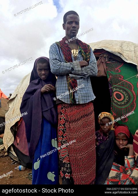 28 June 2022, Somalia, Baidoa: Ali Nur stands with her children in front of the family's makeshift hut. The family had to leave their home village because of...