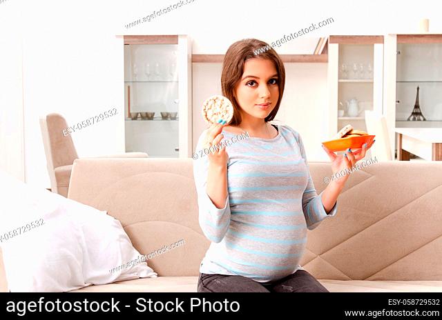 Young pregnant woman sitting on the sofa at home