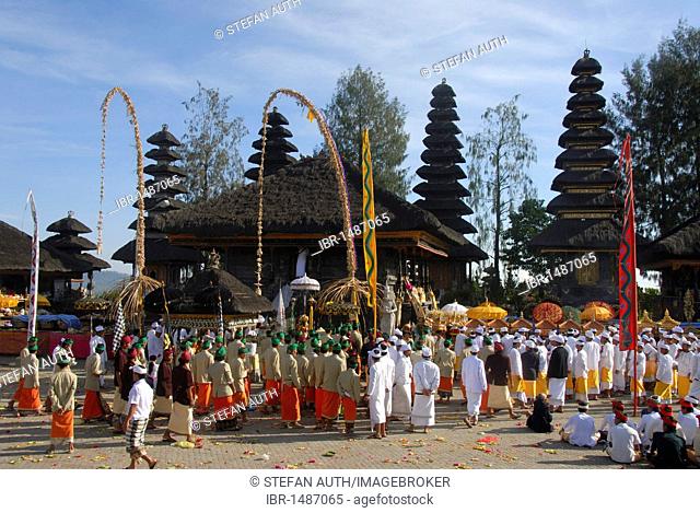 Balinese Hinduism, gathering of believers, ceremony, believers in bright temple dress, colorful flags, Balinese pagodas in the back, Pura Ulun Danu Batur temple