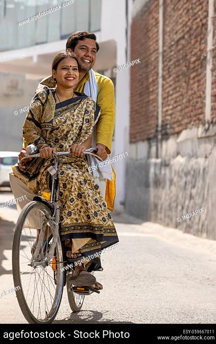 A RURAL COUPLE HAPPILY RIDING A BICYCLE TOGETHER