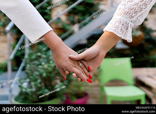 Teenage girl holding young bride's hand in garden
