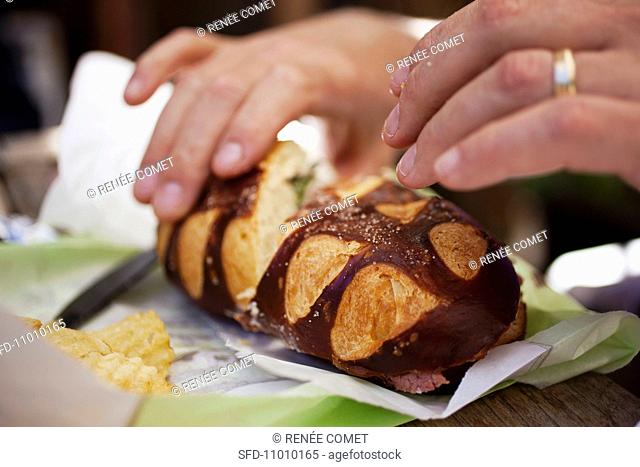 Hand Picking up a Corned Beef Sandwich on Pretzel Brioche San Francisco California