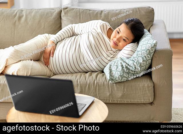 happy pregnant asian woman with laptop at home