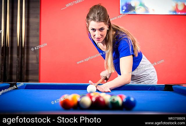Portrait of a beautiful young woman playing billiards