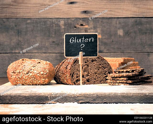 Gluten free written on a small chalkboard with different types of bread as decoration, healthy food concept