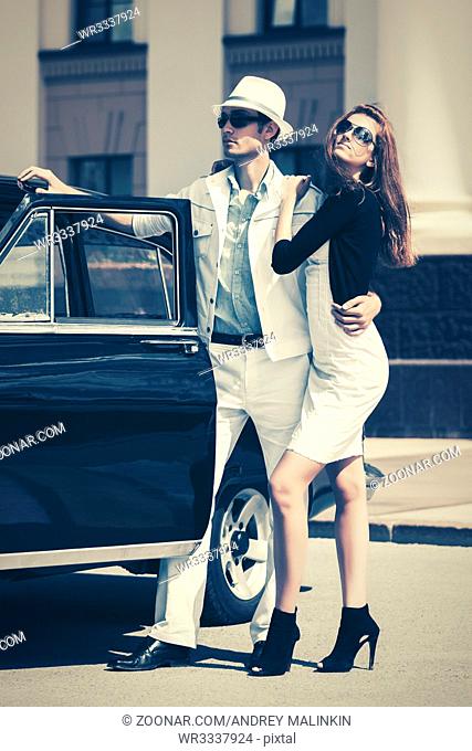 Happy young fashion couple in love next to vintage car