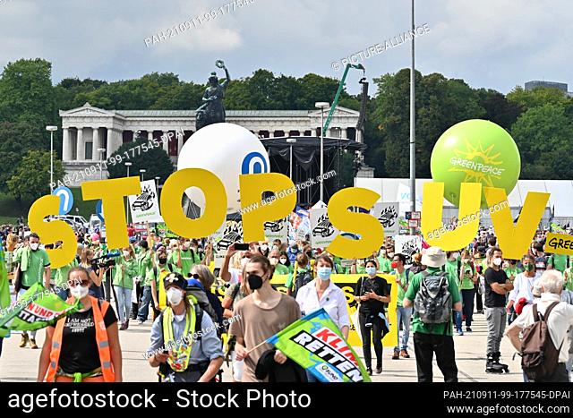 13 March 2020, Bavaria, Munich: Demonstration participants march towards the city center with placards and yellow letters forming the lettering ""Stop SUV""