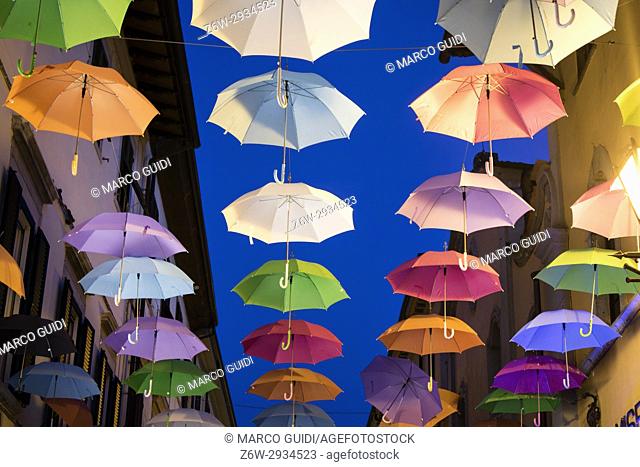 A series of umbrellas of different colors hanging along the main road in Pietrasanta Italy