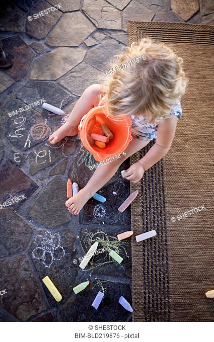 High angle view of girl drawing with chalk on tile