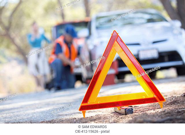 Warning triangle on road with mechanic in background
