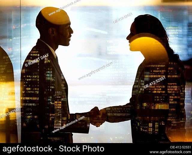 Business people shaking hands at highrise window