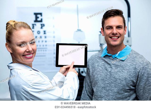 Female optometrist having discussion with patient on digital tablet
