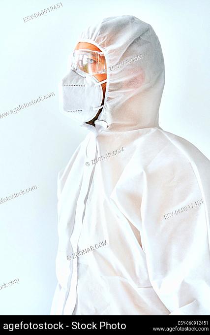 Profile view of doctor in protective medical suit, face mask and glasses on white background